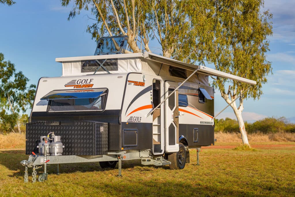 Modern pop-top caravan set-up on grassy area.